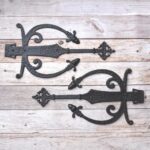 Decorative cast iron spear strap hinge pair with scroll design and antique black finish for barn doors, wooden gates, carriage doors, and farmhouse hardware.