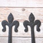 Pair of hand forged wrought iron Fleur de Lis strap hinges for barn doors, wooden gates, carriage doors, and rustic farmhouse décor.