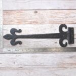 Hand forged wrought iron Fleur de Lis strap hinges with rustic black finish. Heavy-duty decorative hinges for barn doors, gates, sheds, garages, farmhouse, and restoration projects.