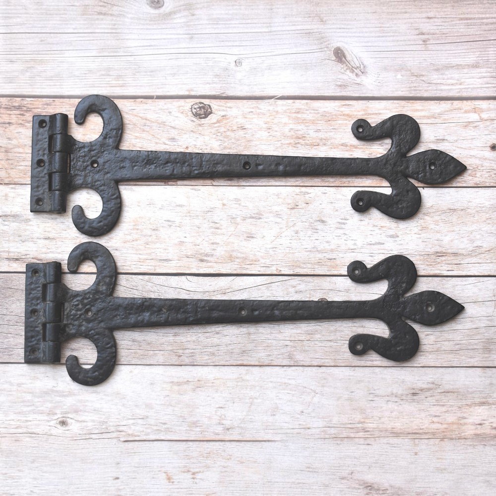 Hand forged wrought iron Fleur de Lis strap hinges with rustic black finish. Heavy-duty decorative hinges for barn doors, gates, sheds, garages, farmhouse, and restoration projects.