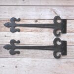 Pair of hand forged wrought iron Fleur de Lis strap hinges for barn doors, wooden gates, carriage doors, and rustic farmhouse décor.