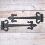 Pair of hand forged wrought iron Fleur de Lis strap hinges for barn doors, wooden gates, carriage doors, and rustic farmhouse décor.