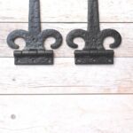 Pair of hand forged wrought iron Fleur de Lis strap hinges for barn doors, wooden gates, carriage doors, and rustic farmhouse décor.