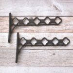 Heavy-duty cast iron hanging basket bracket with decorative quatrefoil design, antique black finish, ideal for hanging flower baskets, lanterns, bird feeders, and planters.