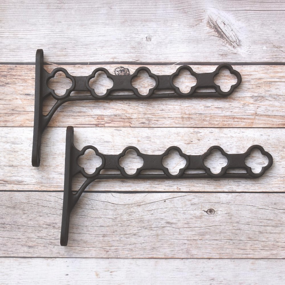 Heavy-duty cast iron hanging basket bracket with decorative quatrefoil design, antique black finish, ideal for hanging flower baskets, lanterns, bird feeders, and planters.