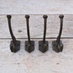 Set of 4 vintage cast iron double coat hooks with decorative detailing and dark rustic finish for coats, hats, bags, and home organization.
