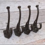Set of 4 vintage cast iron double coat hooks with decorative detailing and dark rustic finish for coats, hats, bags, and home organization.