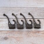 Set of 4 vintage cast iron double coat hooks with decorative detailing and dark rustic finish for coats, hats, bags, and home organization.
