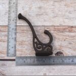 Set of 4 vintage cast iron double coat hooks with decorative detailing and dark rustic finish for coats, hats, bags, and home organization.