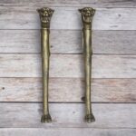 Vintage lion head decorative door pull handles with antique-style finish on a rustic wooden background.