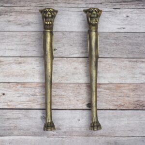 Vintage lion head decorative door pull handles with antique-style finish on a rustic wooden background.