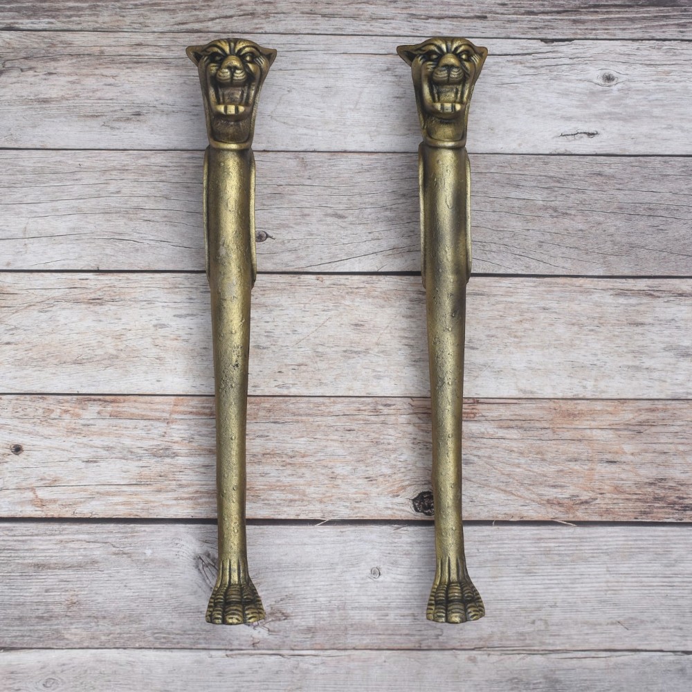 Vintage lion head decorative door pull handles with antique-style finish on a rustic wooden background.