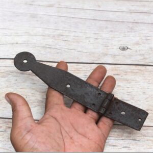 Set of four dark iron penny-end strap hinges on a light wood plank surface.