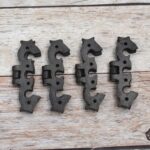 Pair of decorative black cast iron butterfly scroll hinges on a light wooden background.