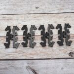 Pair of decorative black cast iron butterfly scroll hinges on a light wooden background.