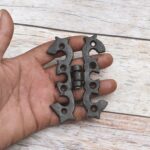 Pair of decorative black cast iron butterfly scroll hinges on a light wooden background.